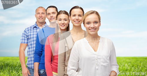 Image of group of smiling people over blue sky and grass