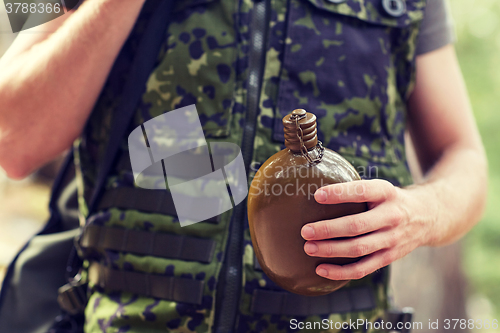 Image of close up of soldier with gun and flask in forest