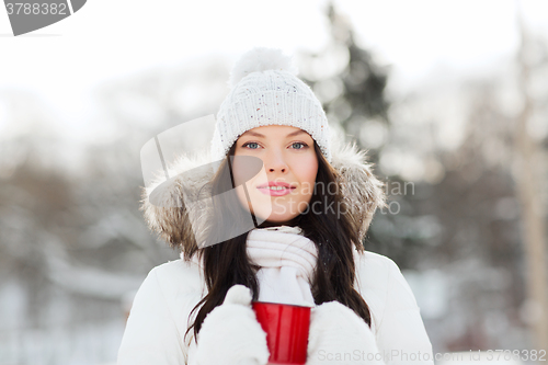 Image of happy young woman with tea cup outdoors in winter