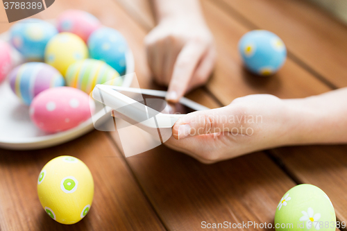 Image of close up of hands with easter eggs and smartphone