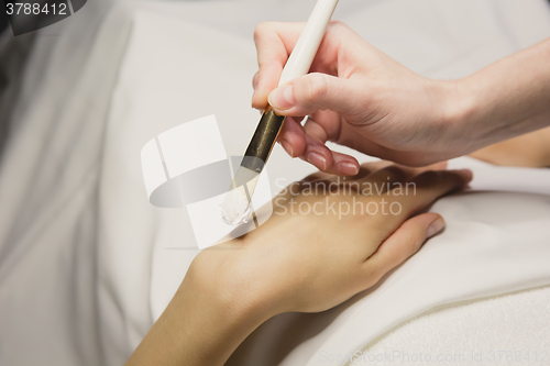 Image of Close up of hands applying cream over table