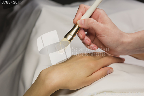 Image of Close up of hands applying cream over table