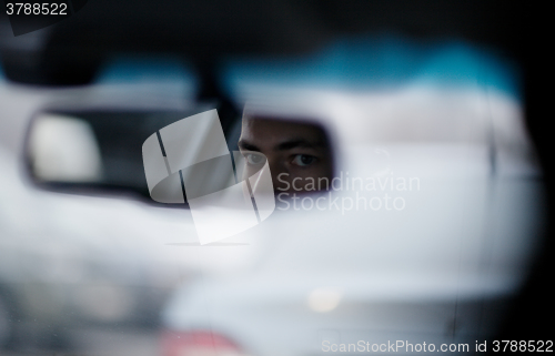 Image of Man looking in the rear view mirror while driving