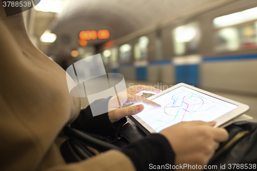 Image of Tablet in female hands showing subway map in underground