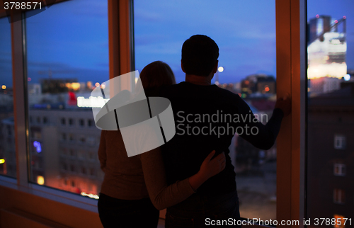 Image of Couple embracing and looking at evening city together