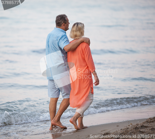 Image of Senior couple enjoying barefoot walk at the seaside