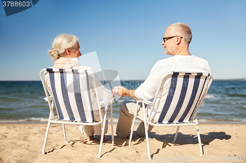 Image of happy senior couple in chairs on summer beach