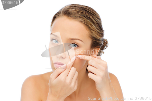 Image of young woman squeezing pimple on her face