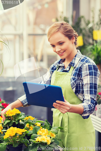 Image of happy woman with tablet pc in greenhouse