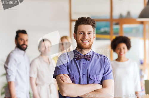 Image of happy young man over creative team in office