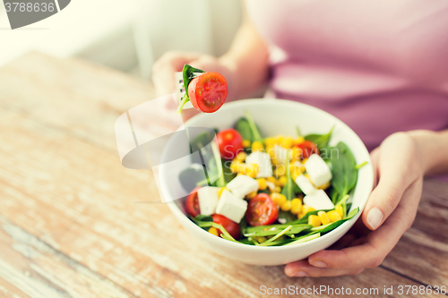 Image of close up of young woman eating salad at home