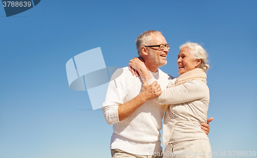 Image of happy senior couple hugging outdoors