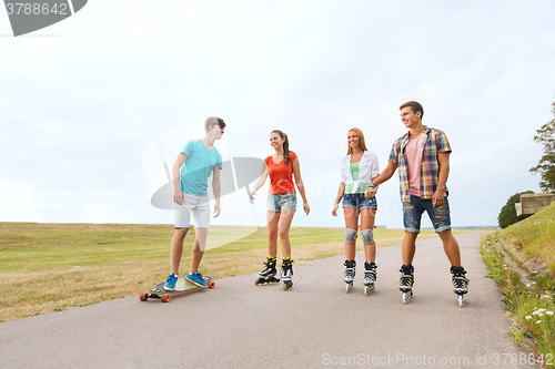 Image of happy teenagers with rollerblades and longboards