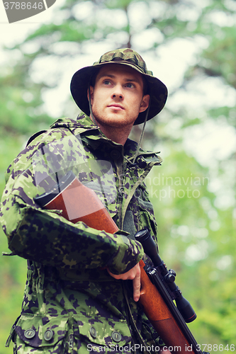 Image of young soldier or hunter with gun in forest