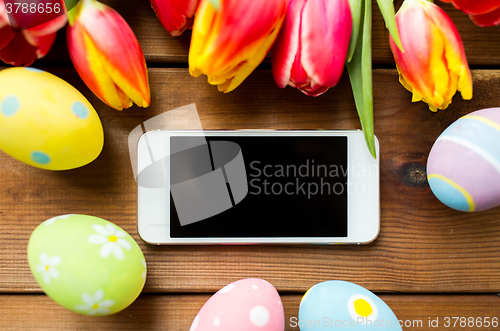 Image of close up of easter eggs, flowers and smartphone