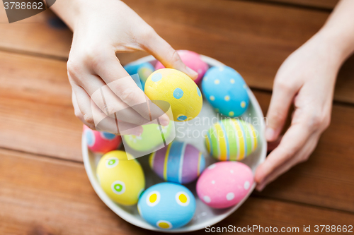 Image of close up of woman hands with colored easter eggs