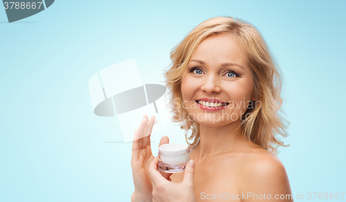 Image of happy woman applying cream to her face