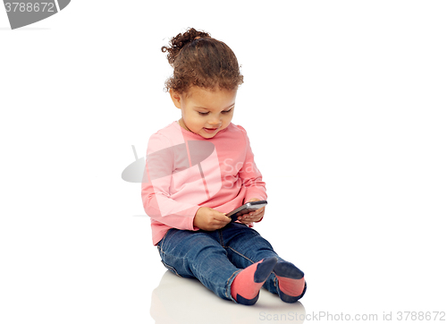 Image of smiling little baby girl playing with smartphone