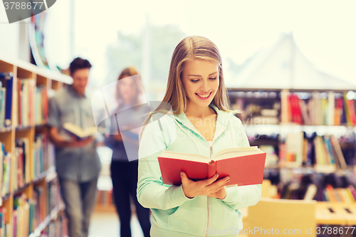 Image of happy student girl or woman with book in library