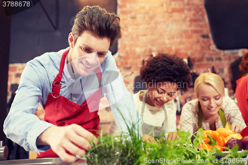 Image of happy friends cooking and decorating dishes