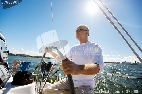 Image of senior man at helm on boat or yacht sailing in sea