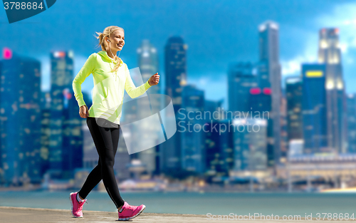 Image of happy woman jogging over city street background