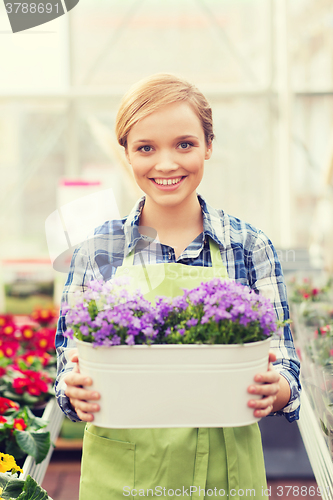 Image of happy woman holding flowers in greenhouse