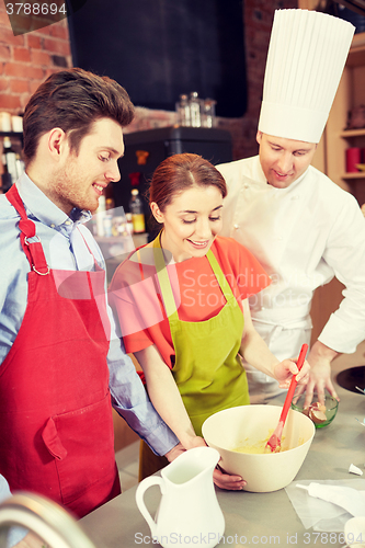 Image of happy couple and male chef cook cooking in kitchen