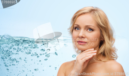 Image of smiling woman with bare shoulders touching face