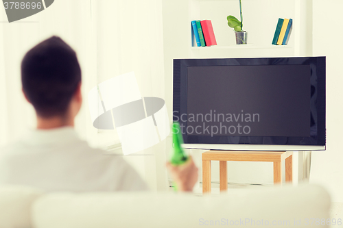 Image of man watching tv and drinking beer at home