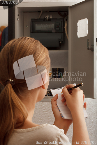 Image of Young woman rewrites the electrical meter readings