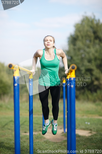 Image of Woman gymnast exercising on parallel bars