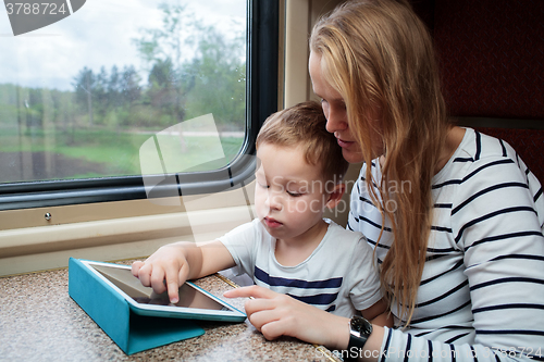 Image of Son and his mom with tablet PC in the train