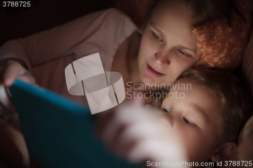 Image of Mother and son with pad in bed at night