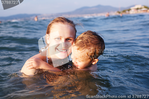 Image of Happy mother teaching her young son to swim