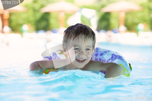 Image of Kid learns to swim using a plastic water ring