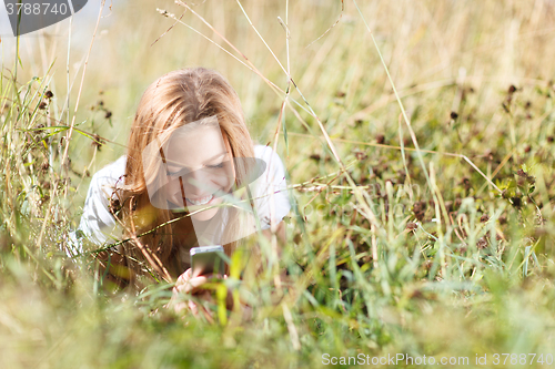 Image of Girl is writing sms on the phone lying in grass