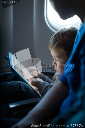 Image of Little boy playing with a tablet in an airplane