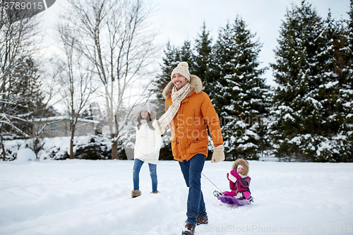 Image of happy family with sled walking in winter outdoors