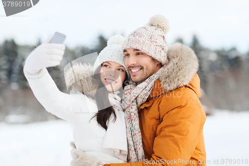 Image of happy couple taking selfie by smartphone in winter