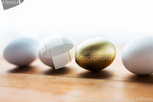 Image of close up of golden and white easter eggs on wood