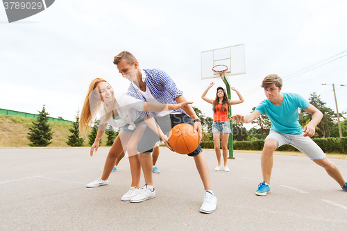 Image of group of happy teenagers playing basketball