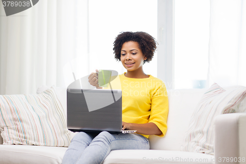 Image of happy african american woman with laptop at home