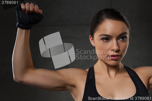 Image of young woman flexing muscles in gym