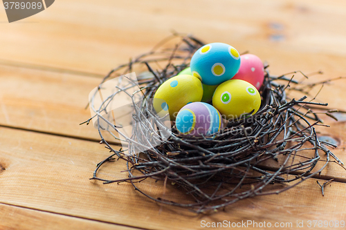 Image of close up of colored easter eggs in nest on wood