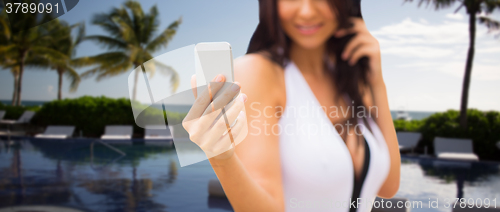 Image of young woman taking selfie with smartphone on beach