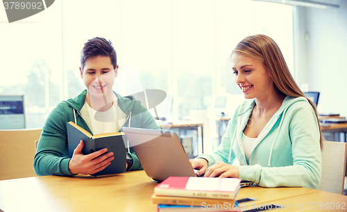 Image of happy students with laptop and books at library