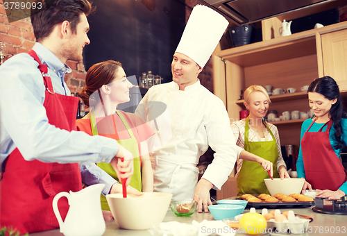 Image of happy friends and chef cook baking in kitchen