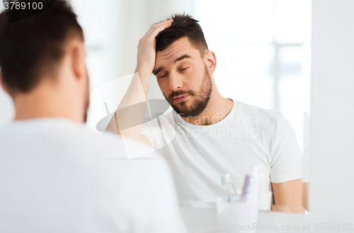Image of sleepy young man in front of mirror at bathroom