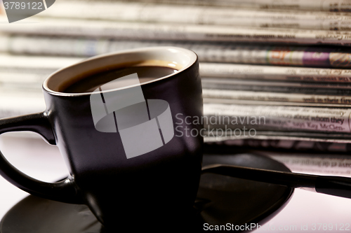 Image of Cup of coffee and newspapers pile on the table.